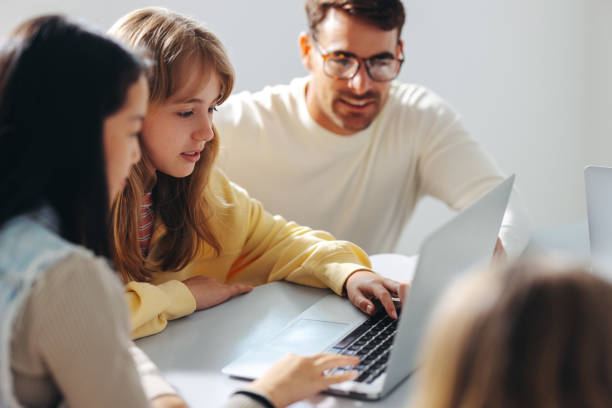 A young girl with light brown hair sits between her mother and father and reviews information on a laptop.