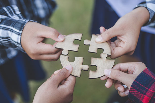 Four children hold 4 puzzle pieces close together, but not fully connecting them.