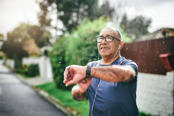 An older man with light brown skin stops his smart watch after completing an outdoor workout.