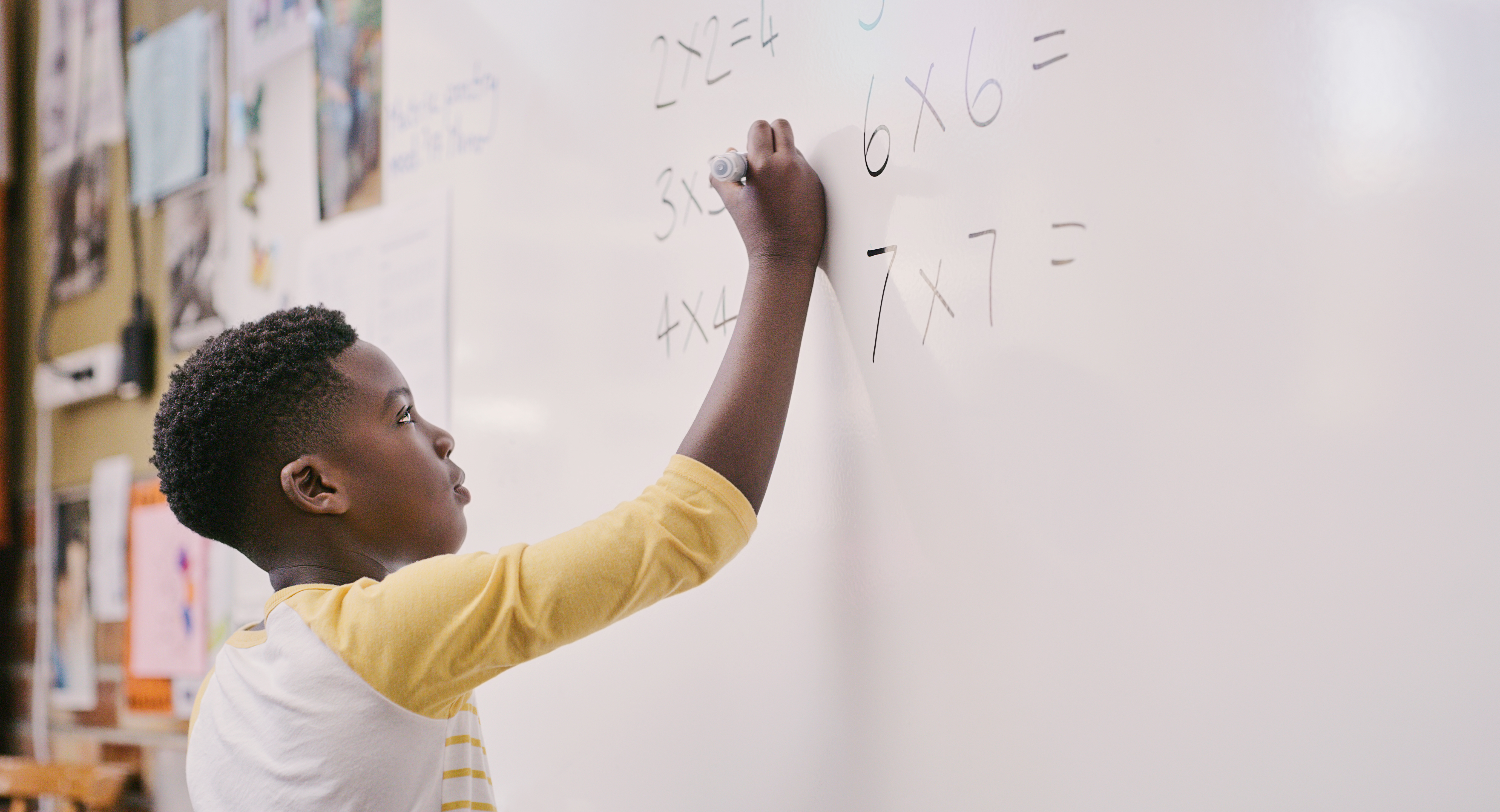 A young student writes on a whiteboard.